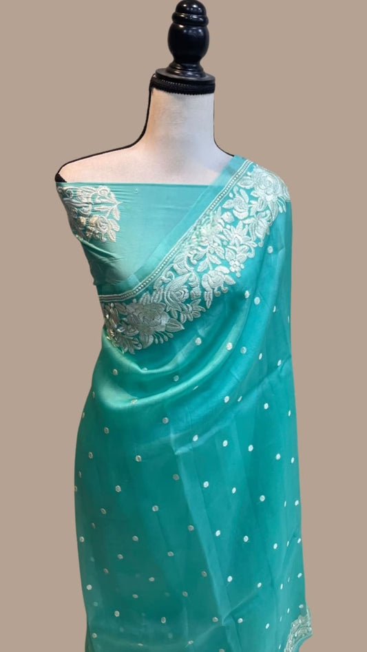 Teal draped organza saree with floral embroidery at the pallu and dotted pattern
