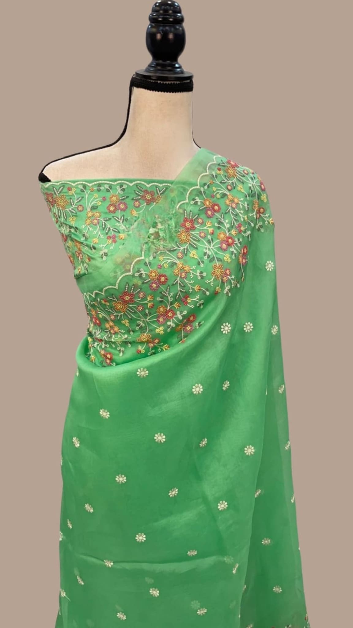Green organza saree on mannequin with embroidered pallu and delicate floral motifs