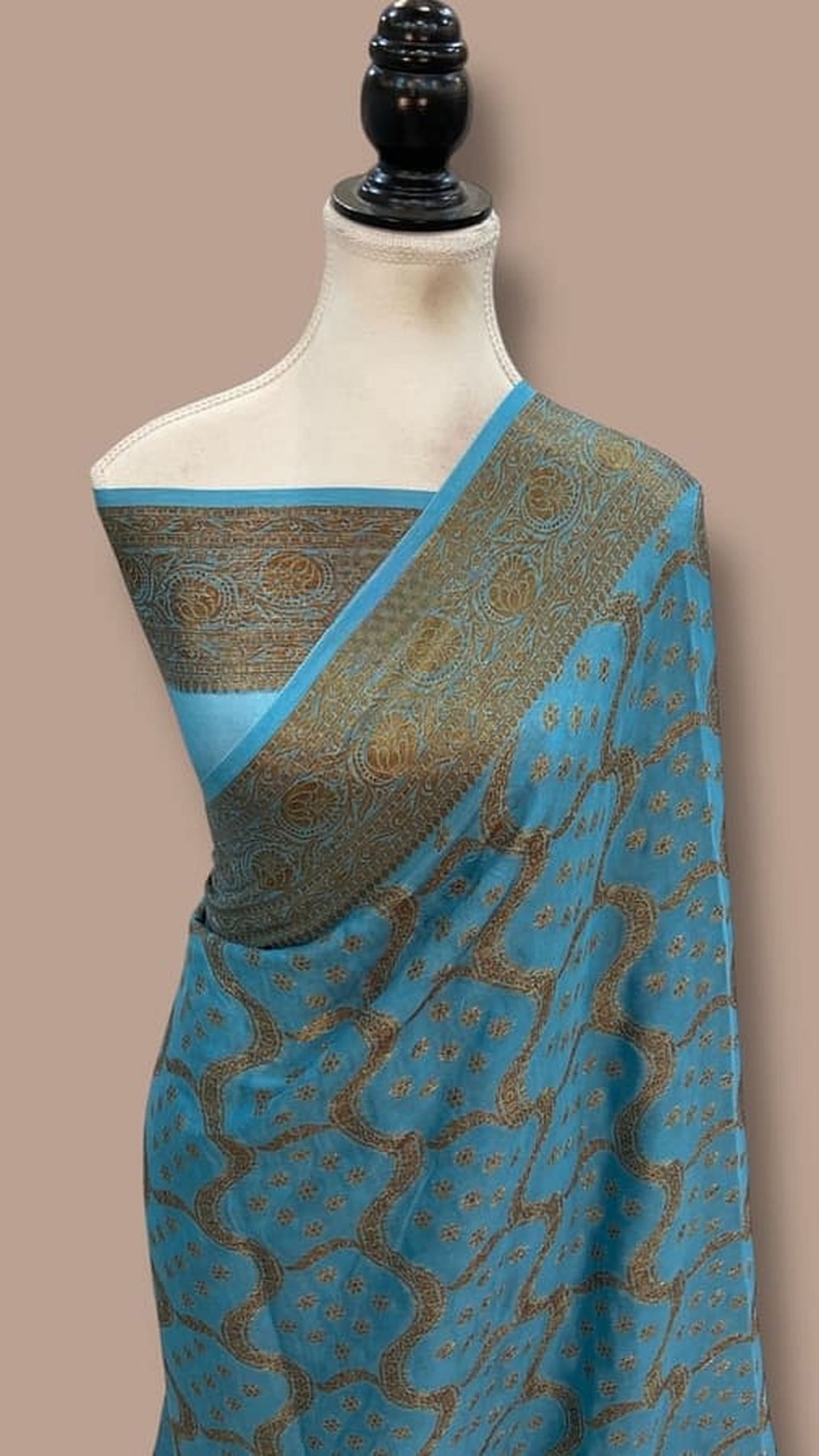 Turquoise blue chiffon saree with gold zari border and decorative pallu draped at shoulder
