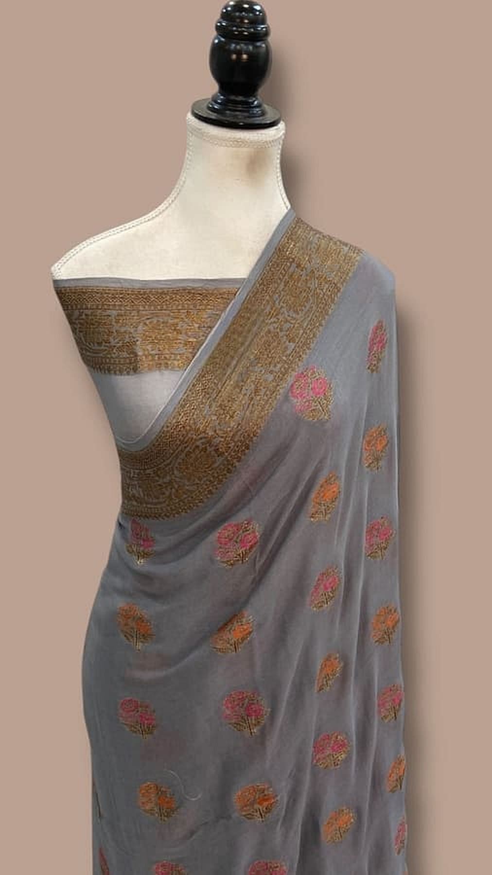 Grey chiffon saree draped with gold-brown pallu border and multicolor floral motifs
