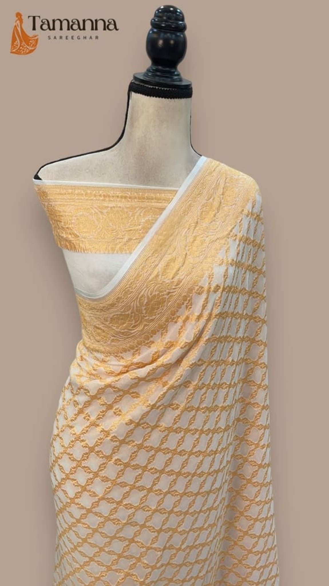 Draped saree on mannequin: cream base with gold jaal pattern and wide zari border