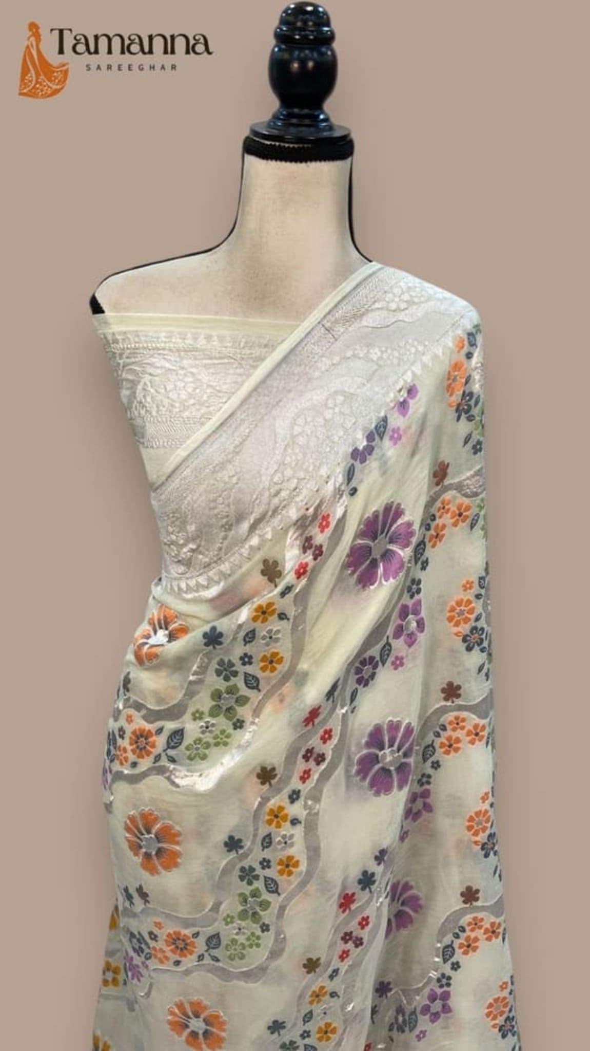 White saree drape with floral sprigs and jacquard border, shown on mannequin
