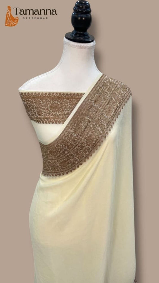 Cream saree on mannequin with wide zari border across pleats and decorative pallu