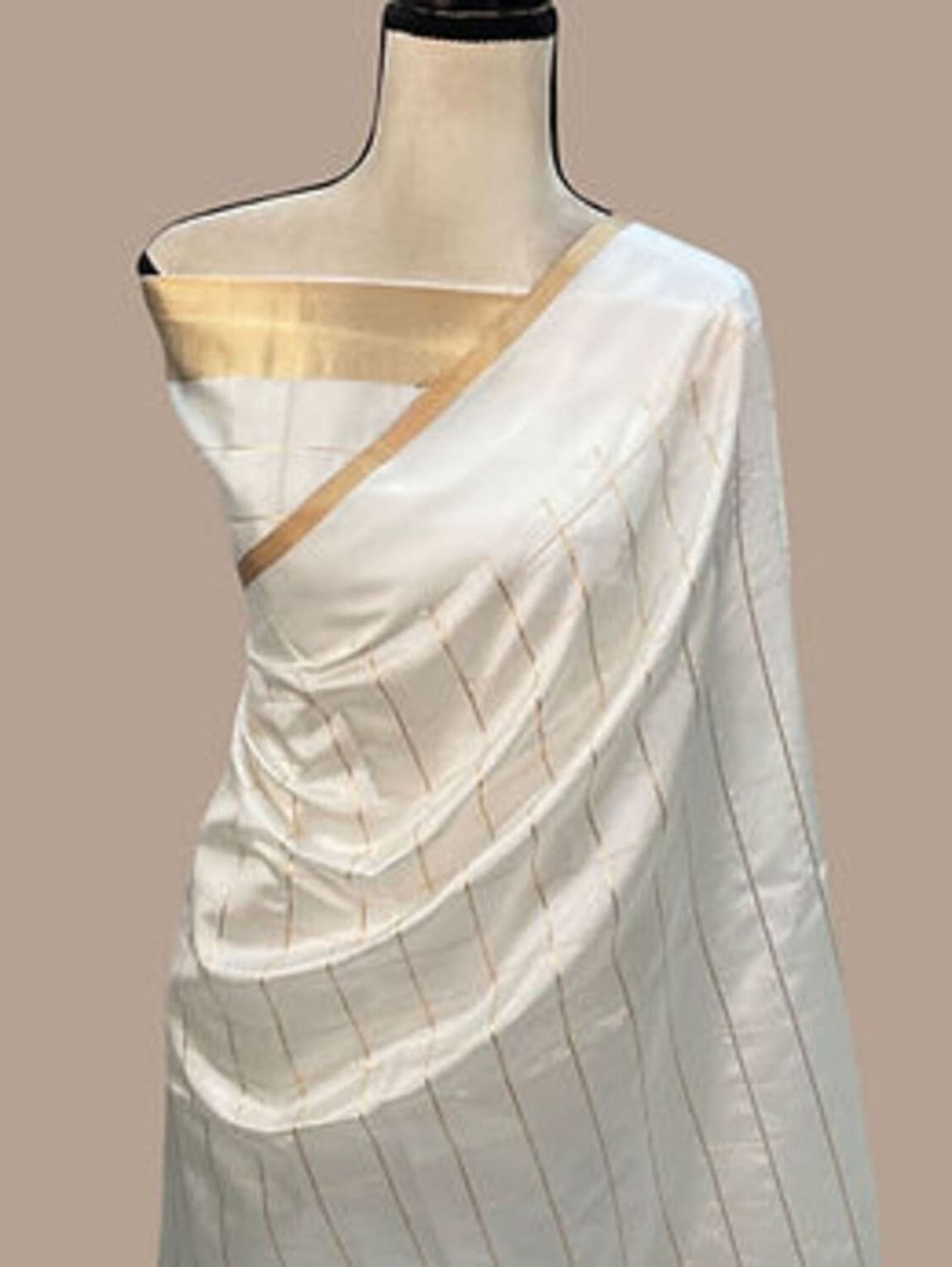 White silk saree with gold border on mannequin, checked pallu and body