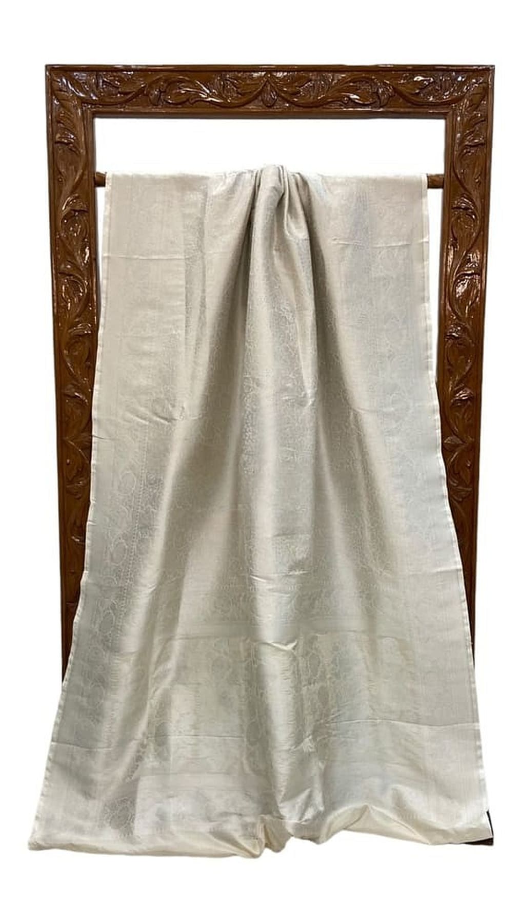White Banarasi silk saree draped on display frame, woven border and patterned fabric