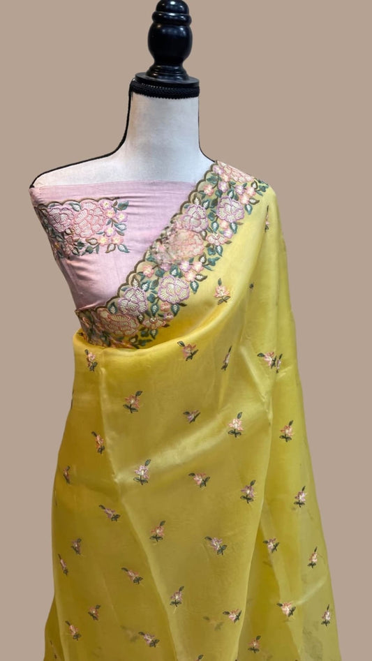 Yellow organza saree draped on mannequin, pink border with floral embroidery