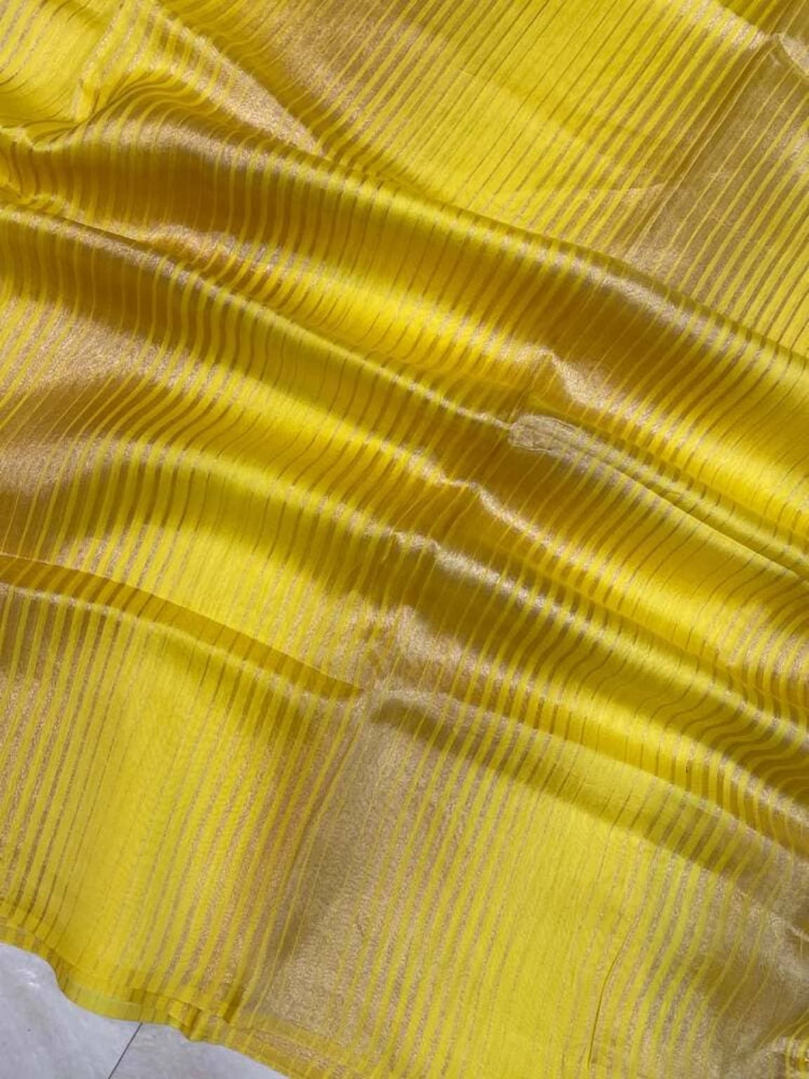 Close-up of yellow saree border with horizontal bands and sheer woven sheen