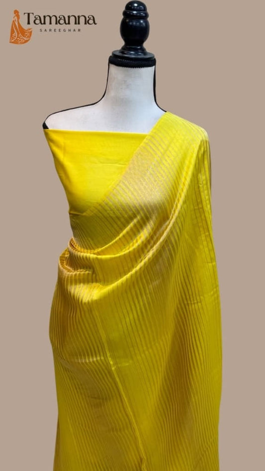Yellow saree draped over mannequin with shimmering woven pattern and pallu
