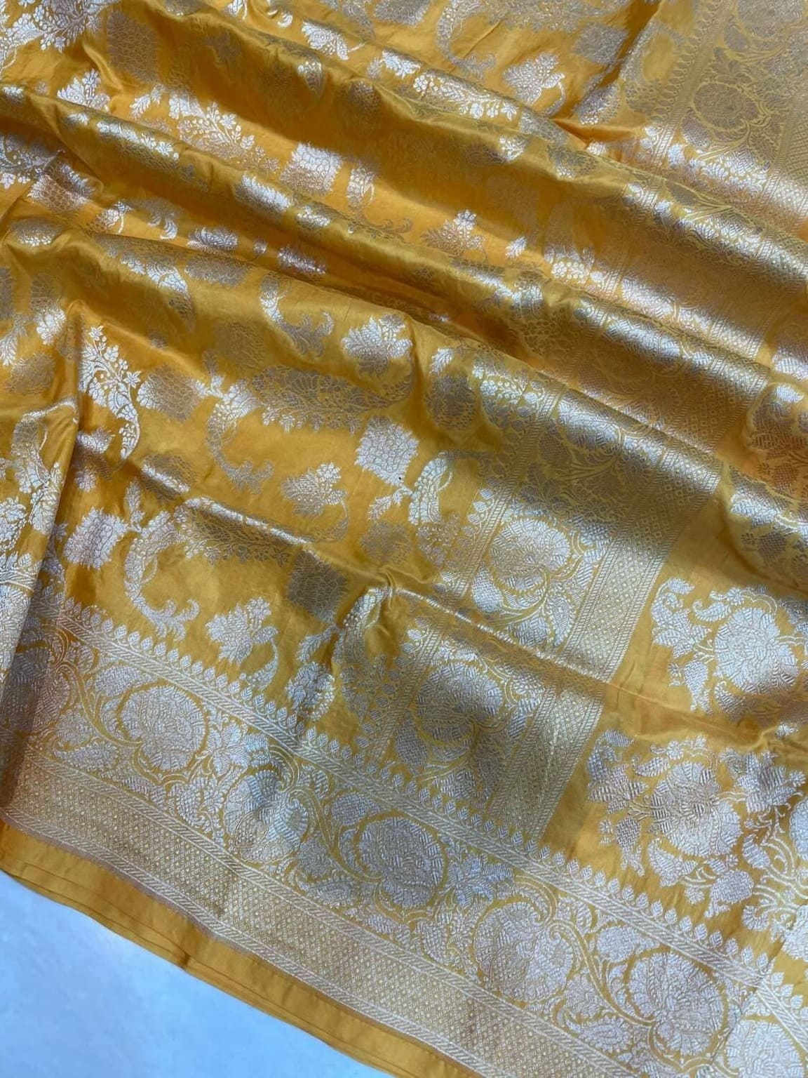 Close-up of yellow silk saree with gold jaal and floral motifs