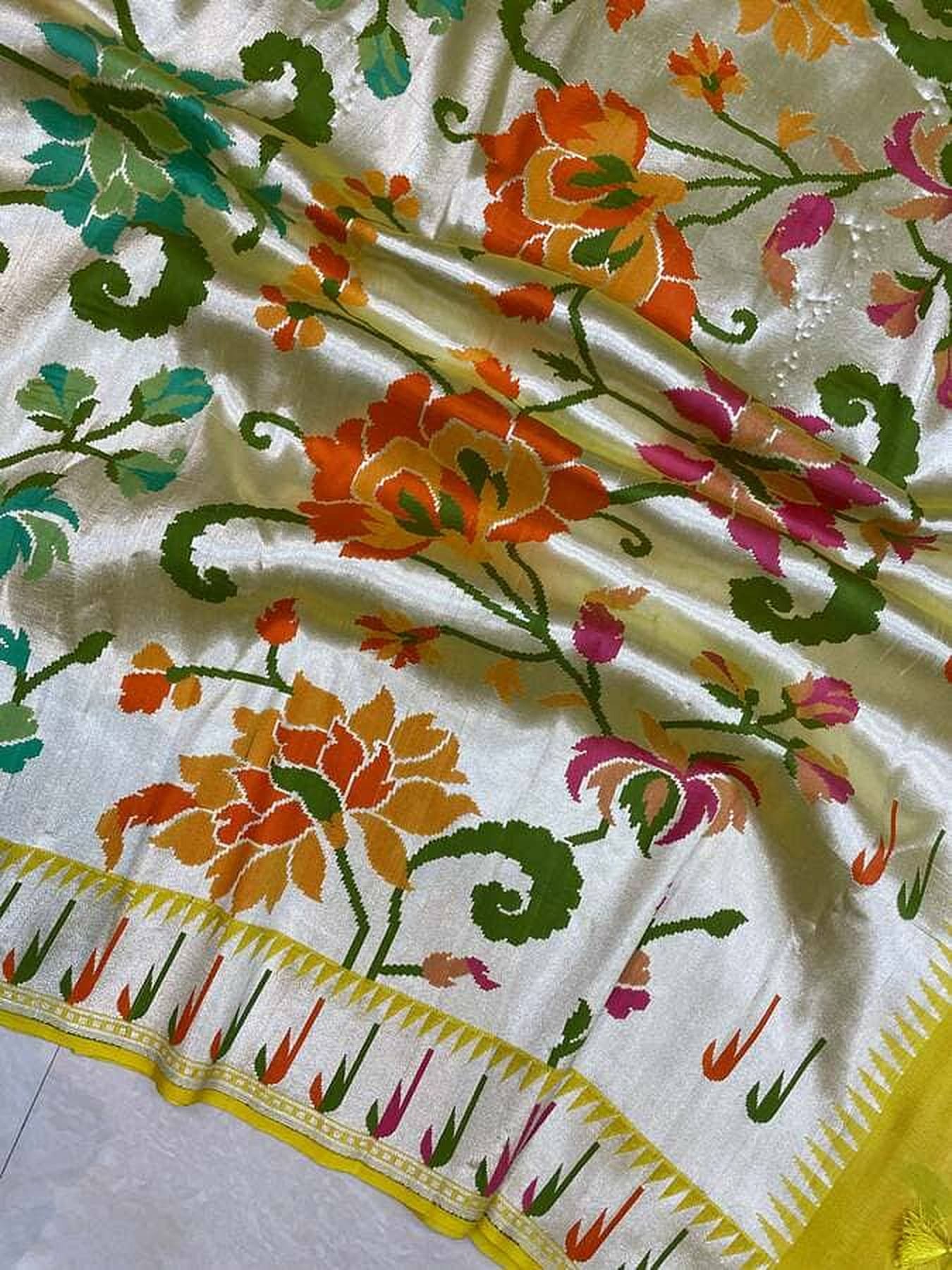 Cream silk saree close-up with floral vines and gold striped border